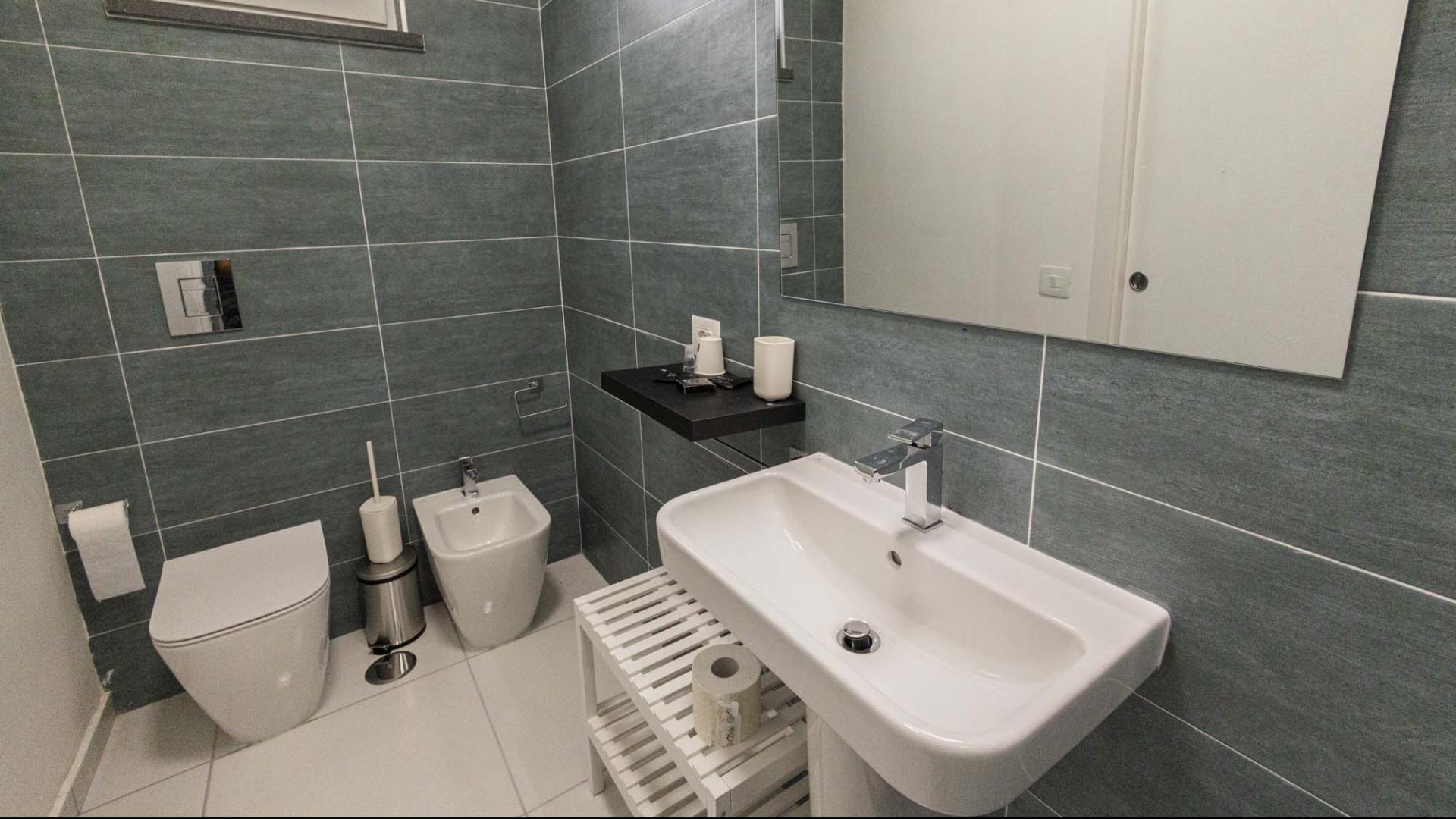 Bagno moderno e ordinato, piastrelle grigie, atmosfera pulita e minimalista.