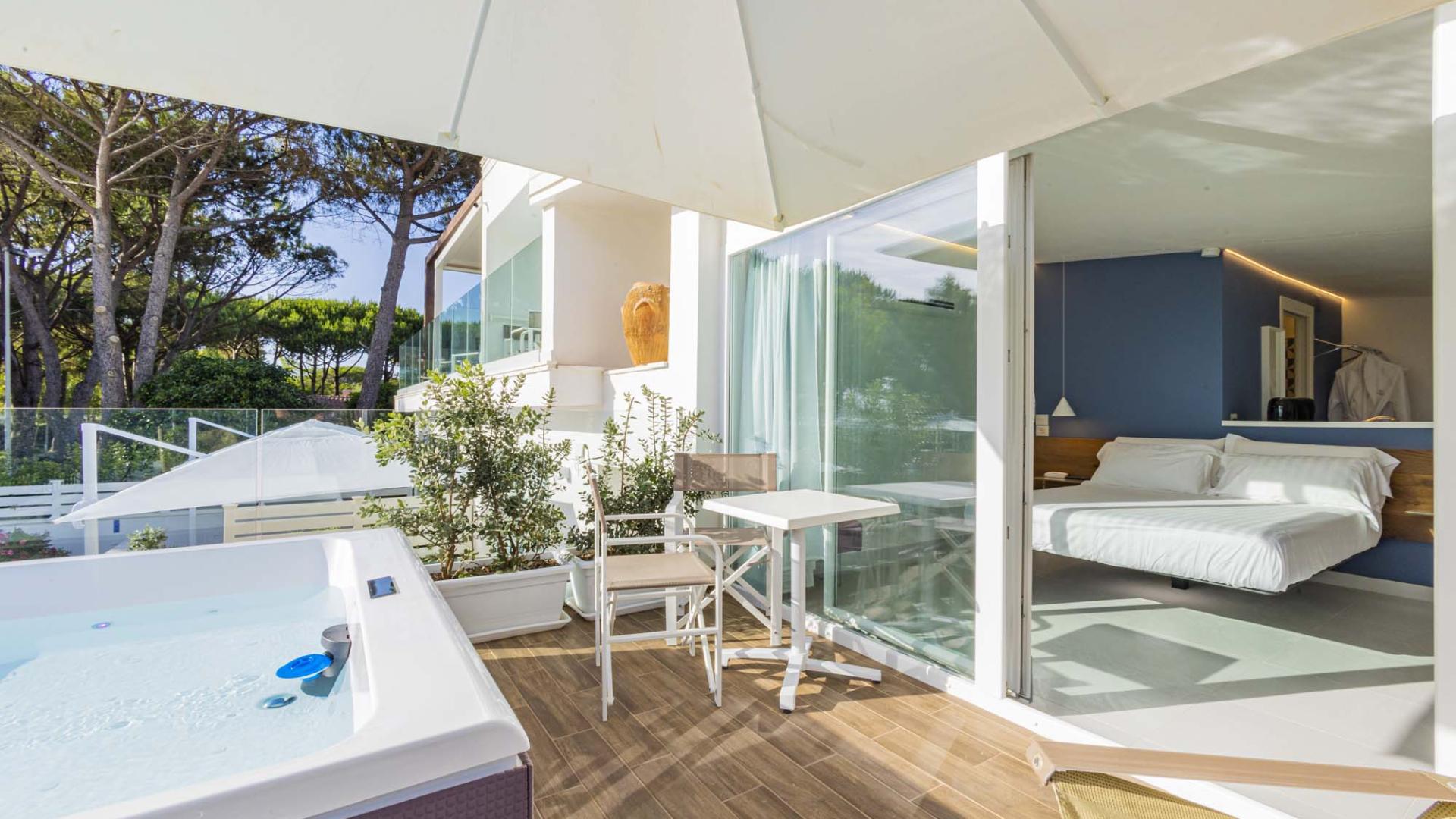 Terrazza con jacuzzi, natura rigogliosa e camera luminosa, perfetta per relax e tranquillità.